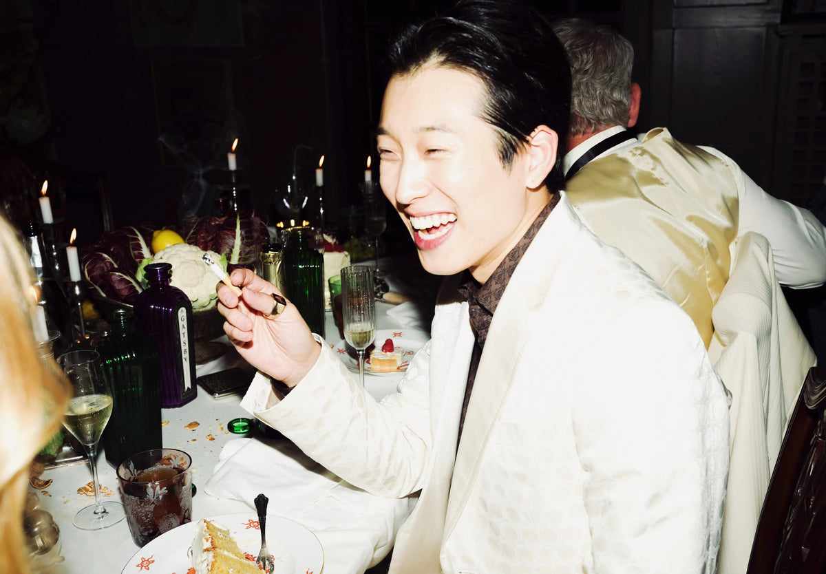 A guest laughing at a candlelit dinner table with bottles of Gatsby Gin and coupes of champagne