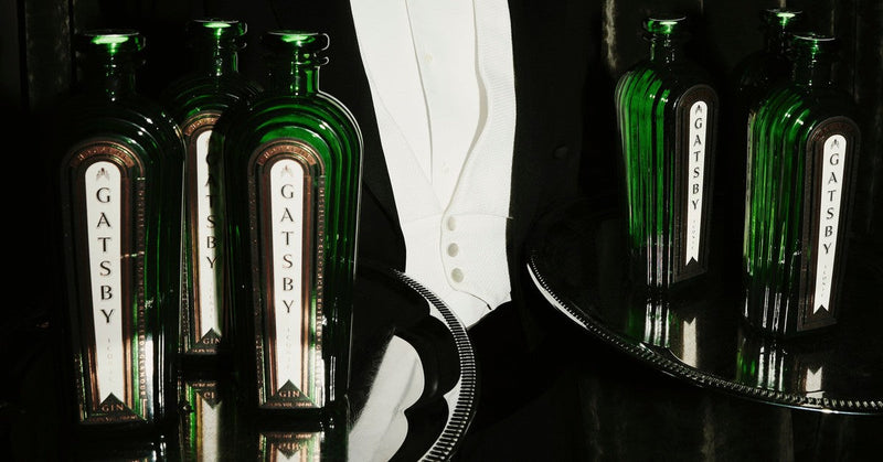 Bottles of Gatsby Gin on two silver trays, carried by a waiter in evening dress.